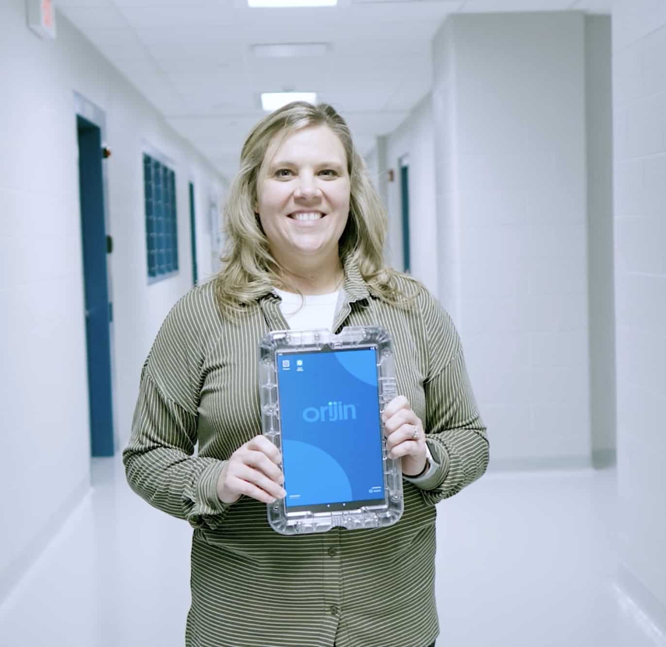 Crystal Petty in a hallway, holding up an Orijin laptop.